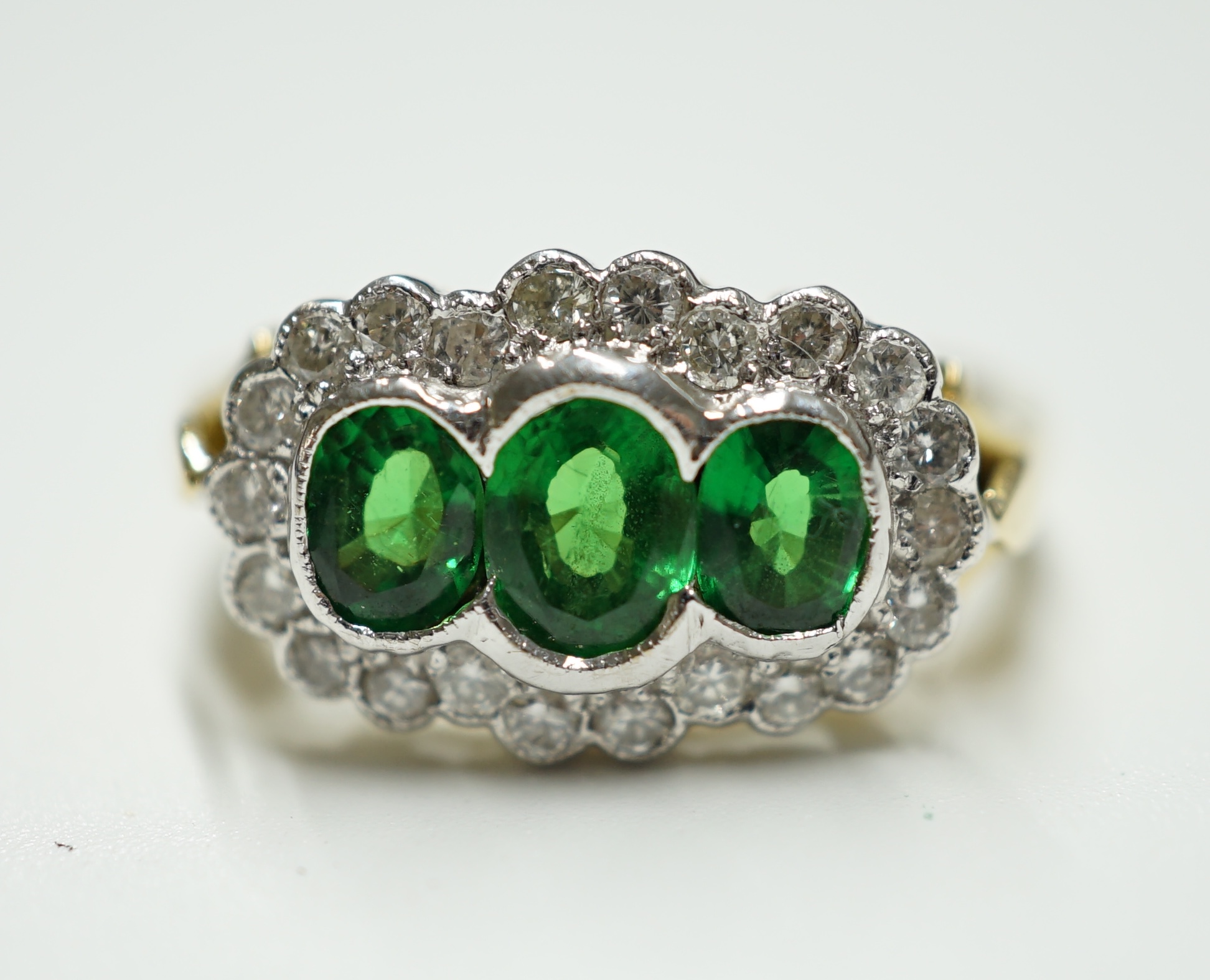 An 18ct, three stone tsavorite garnet and diamond set triple cluster ring, size Q, gross weight 5.2 grams. Condition - Good